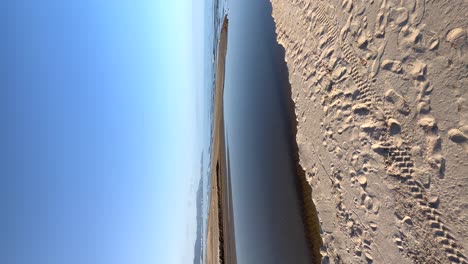 mouth of a river that crosses the beach in the direction of the sea, vertical view for mobile