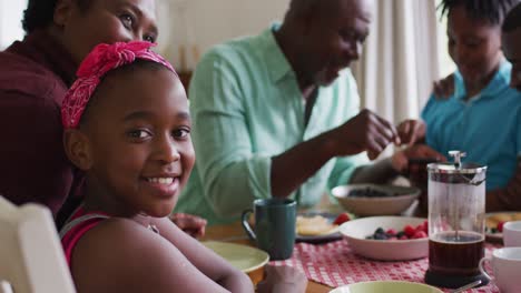 Porträt-Eines-Afroamerikanischen-Mädchens,-Das-Lächelt,-Während-Es-Zusammen-Mit-Seiner-Familie-Zu-Hause-Frühstückt