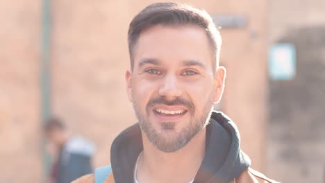 caucasian bearded man looking at camera and smiling in the street