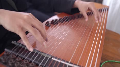 close-up of a person playing a traditional indonesian zither