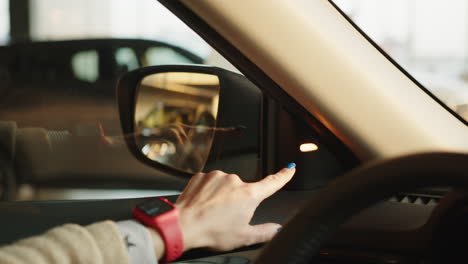 mujer ajustando el espejo lateral del coche