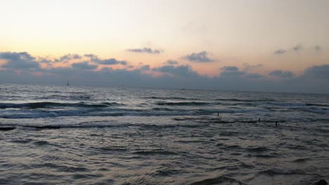 the beach at sunset, waves breaking on the beachship sails deep into the sea, orange-colored sunset,tel aviv beach