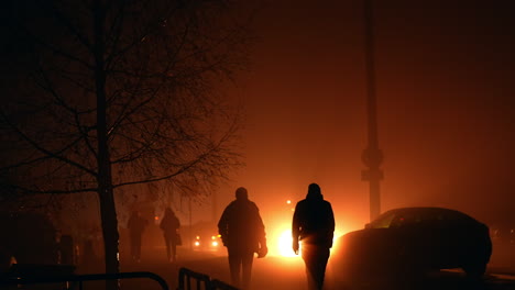 silhouettes of people walking in foggy night city