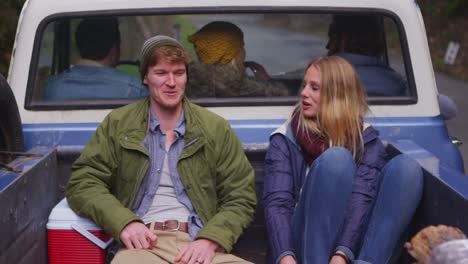 a couple sits in the back of a pickup truck as it pulls away 1