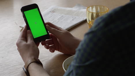 man using smartphone with green screen to make video call