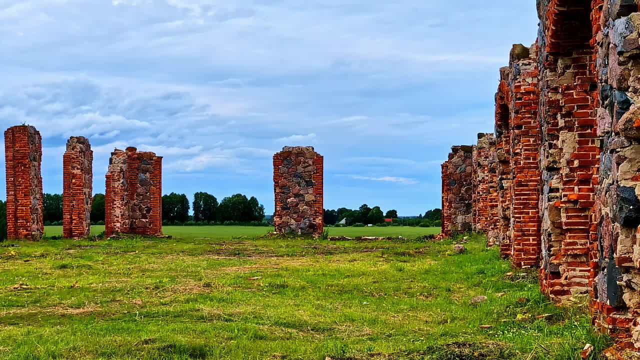 Brick and Stone Ruins in Open Field Beneath Moody Overcast Sky in Latvia