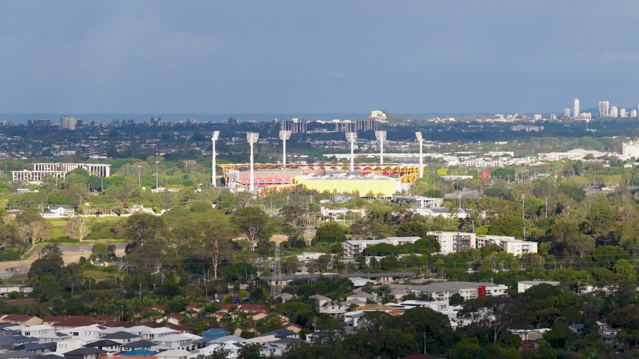 Drone footage captures a panoramic view of Carrara Stadium and lush surroundings under dynamic lighting in Gold Coast, Australia