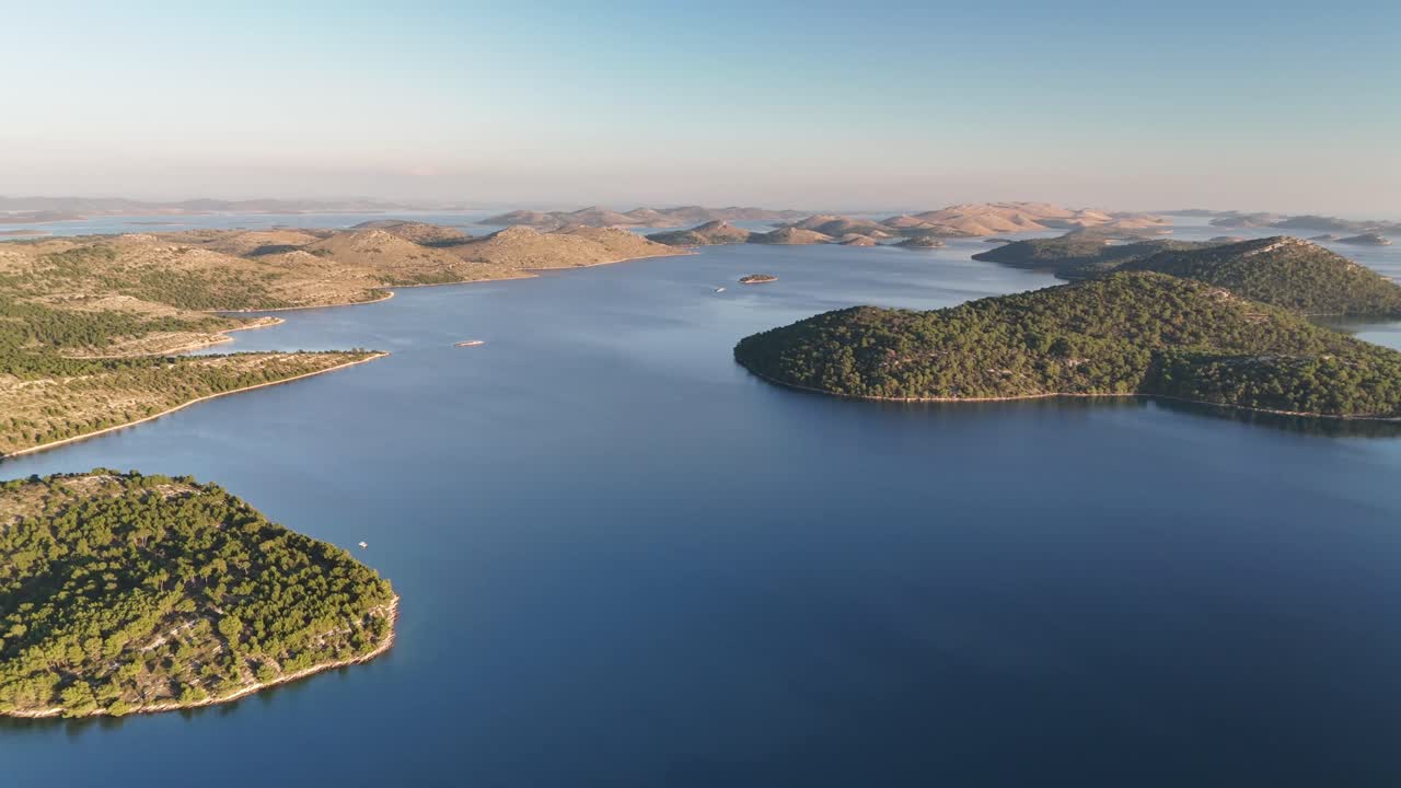Drone turns over Telascica bay, revealing Dugi Otok’s hilly terrain, lush forests, and scattered islands in sunset light