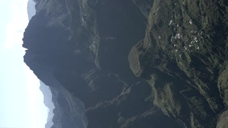 Vertical-ungraded-Video-of-a-drone-filming-a-giant-crater-and-huge-mountain-then-turning-and-flying-towards-the-edge