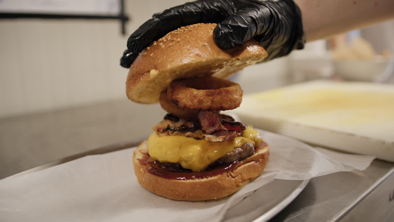 Chef Finalizing The Creation Of The Gourmet Burger With The Top Piece Of Bread