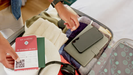 Close-up-of-hands-of-biracial-man-packing-suitcase-in-bright-bedroom