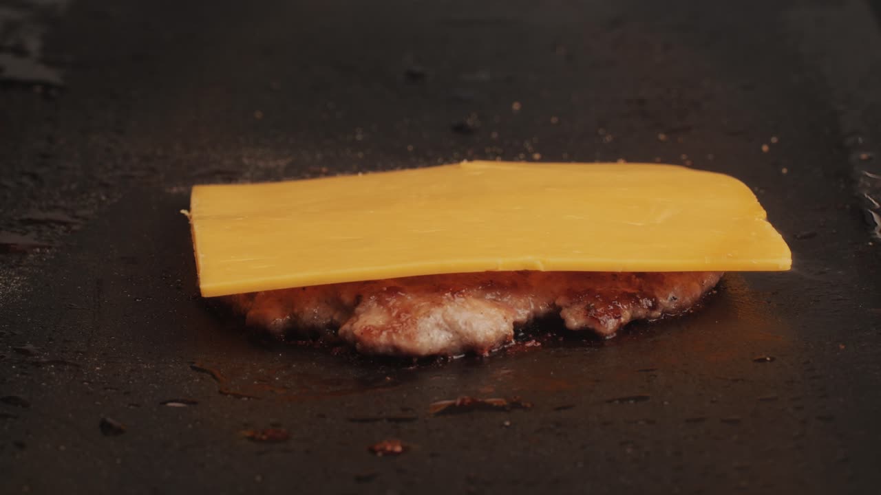 Cooking American fat smash burger with cheese slice on top on grill close-up. Beef or pork cutlet smashing by burger press. The chef in kitchen of the restaurant making cutlets for burgers - smash burger beefsteak. Fast and street food concept.