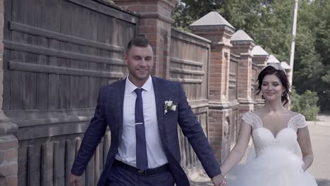 slow-motion-young-wedding-couple-runs-near-brown-fence