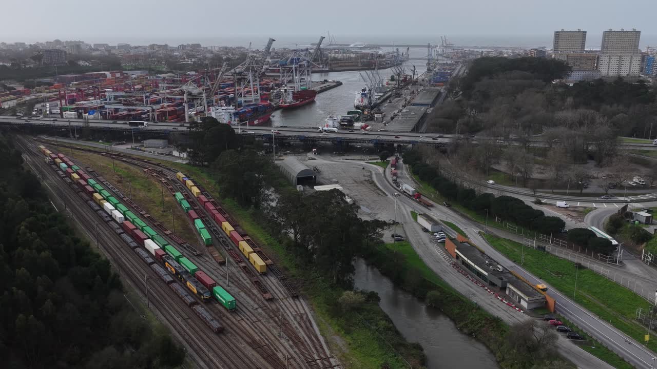 Flod og jernbanespor med togvogne og shippingcontainere ved siden af en fragthavnsterminal