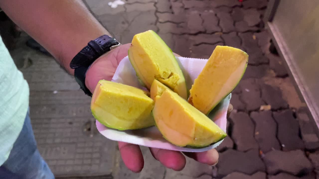 primer plano de un hombre disfrutando de un helado indio llamado kulfi de mango, que es dulce y cremoso y se prepara con mangos en lugar de los ingredientes habituales en el helado