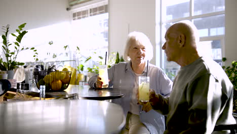 senior couple drinking limonade and talking while they are sitting in a bar at sunset