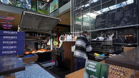 man preparing coffee at bar in spitalfields market, london, uk. wide shot
