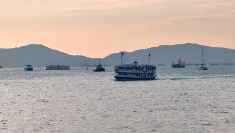 Star-Ferry-with-special-painting-crossing-the-busy-Victoria-harbour-with-other-vessels-during-sunset