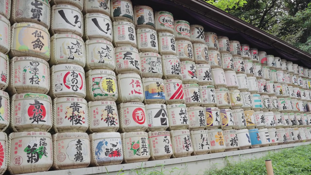 Video dengan gerakan panning lebar tong sake yang dihias indah di Kuil Meiji Jingu pada siang hari di Taman Yoyogi, Tokyo.