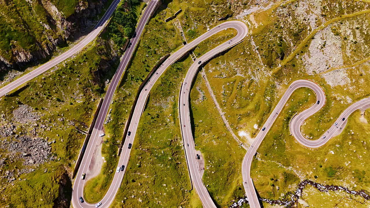 Transfagarasan road with cars moving along winding curves. Vehicles drive on the Transfagarasan serpentine road through the mountains of Romania