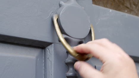 close up of a man using a door knocker to knock on a door