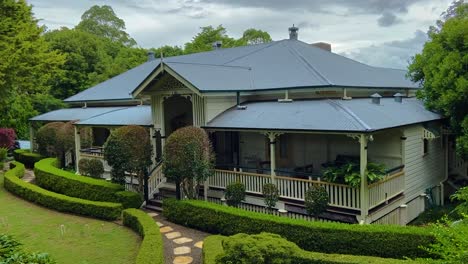 Toma-Panorámica-Suave-Y-Lenta-De-Una-Clásica-Casa-Rural-Tradicional-De-Queensland,-Enclavada-En-Un-Jardín-Cuidadosamente-Cuidado-En-Lo-Profundo-Del-Interior-De-Queensland