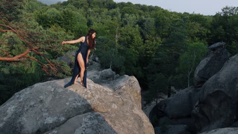 woman walks along the edge of a cliff and looks at the sun. flying gown fluttering in wind