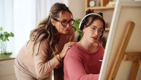 mujer enseñando a un joven adulto a pintar