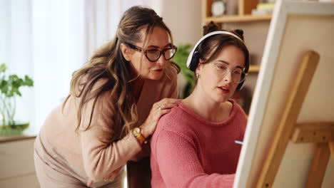 woman teaching a young adult how to paint