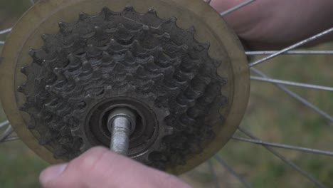 los dedos del hombre desenroscan la tuerca del eje de la rueda de la bicicleta