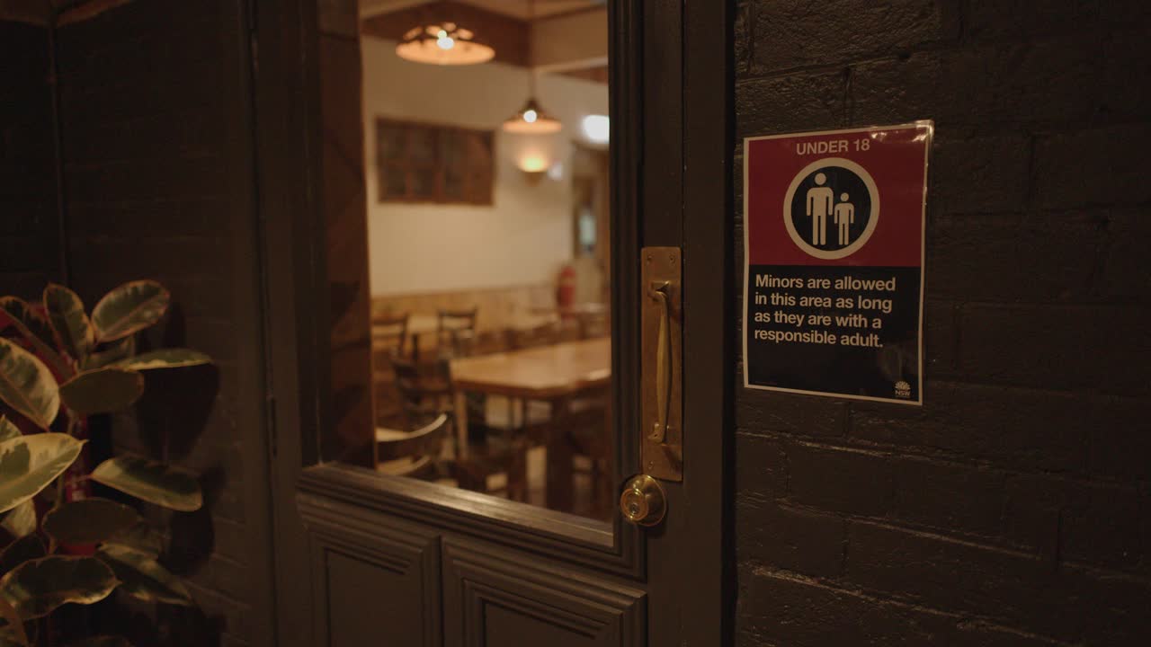Hand opens restaurant door at night, revealing warmly lit, empty dining area, interior view