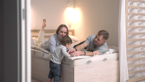 Rear-View-Of-A-Baby-Taking-His-First-Steps-Towards-The-Bed-Where-His-Parents-Are