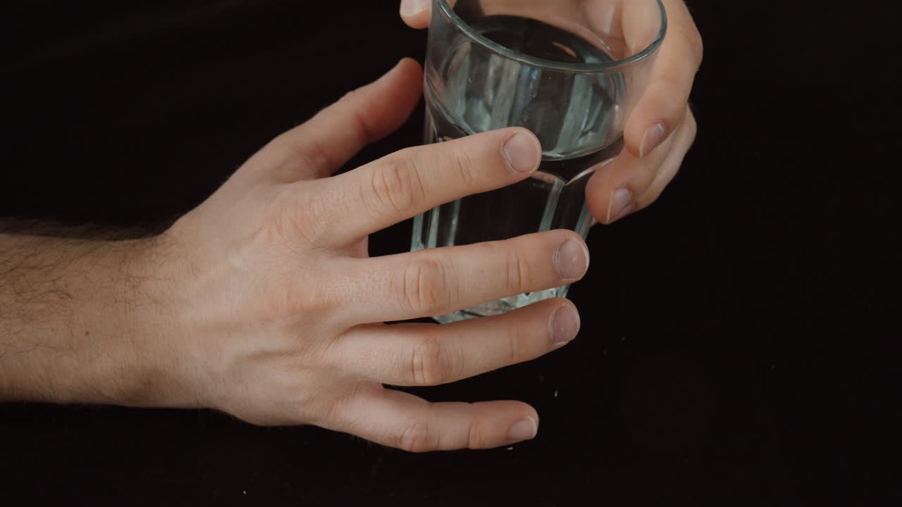 Primo piano di mani che tengono un bicchiere con rigidità visibile, che rappresenta mobilità ridotta, disagio e limitazione nella vita quotidiana.