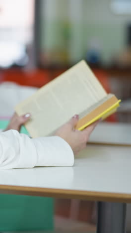 primer plano de una mujer leyendo un libro en un centro comercial con café en la mesa, otros compradores y personas que pasan borrosas en el fondo, capturando un momento pacífico y relajado en una zona comercial concurrida
