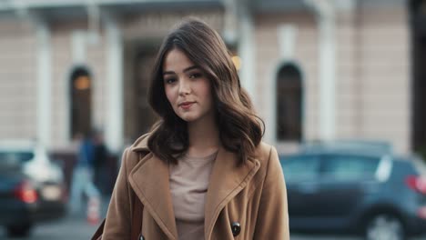 Portrait-Of-A-Beautiful-Brunette-Girl-Smiling-At-The-Camera-While-City-Traffic-Circles-Behind-Her