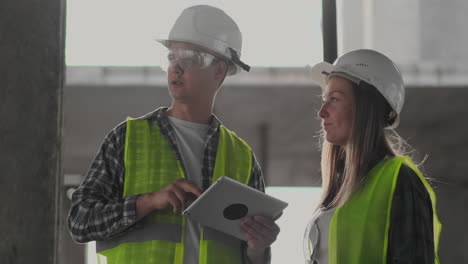 Construction-worker-and-engineer-talking-at-construction-site-site.-Workers-in-helmets-at-building-area.-Portrait-of-construction-engineers-working-on-building-site.-concept-of-modern-construction