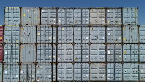 aerial view of numerous shipping containers tightly stacked in a busy shipping yard. the containers are marked with various codes, showcasing the vibrant logistics activity of the port.