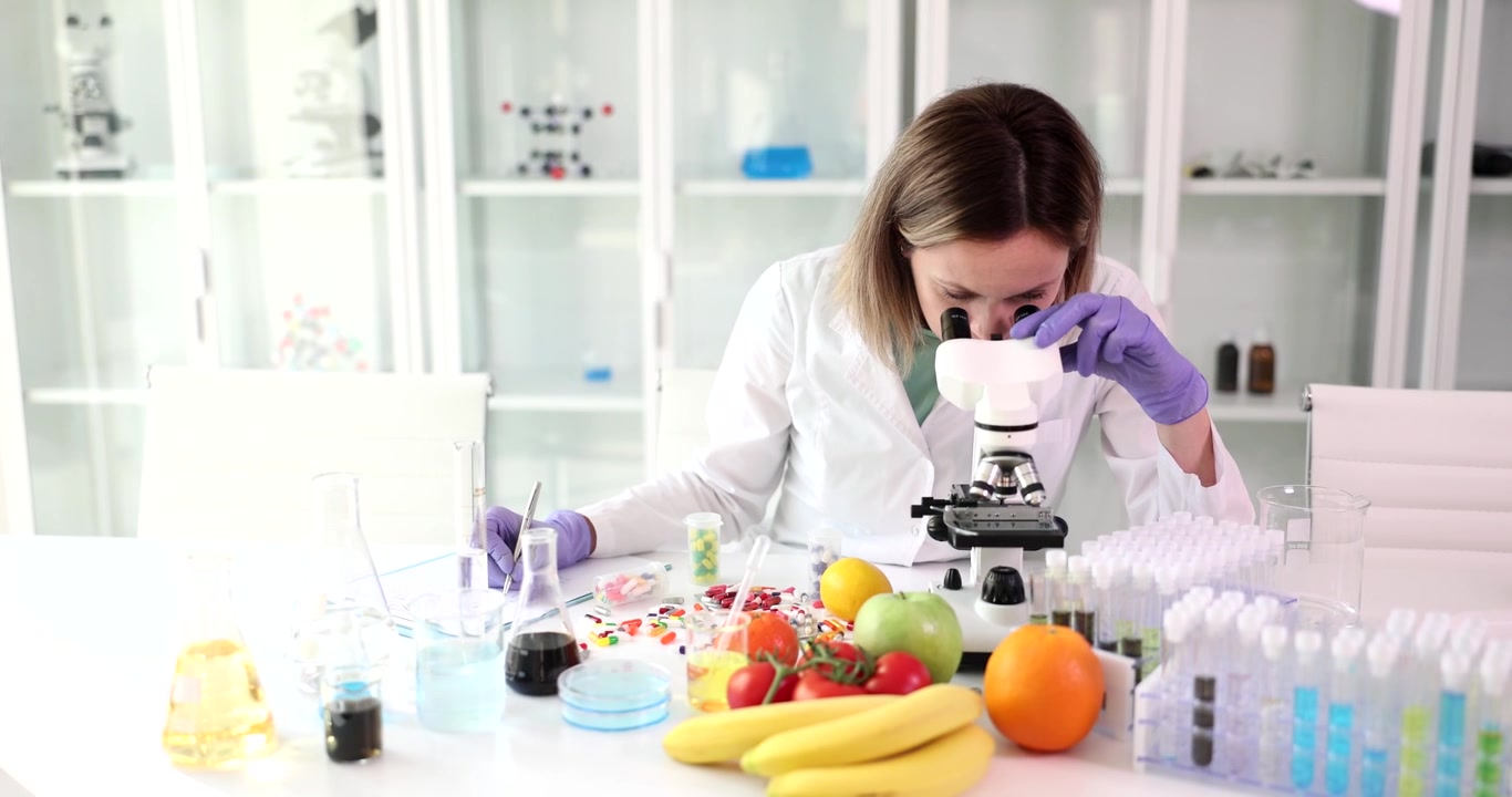 Cientista estuda amostra de alimento sob microscópio durante trabalho de laboratório