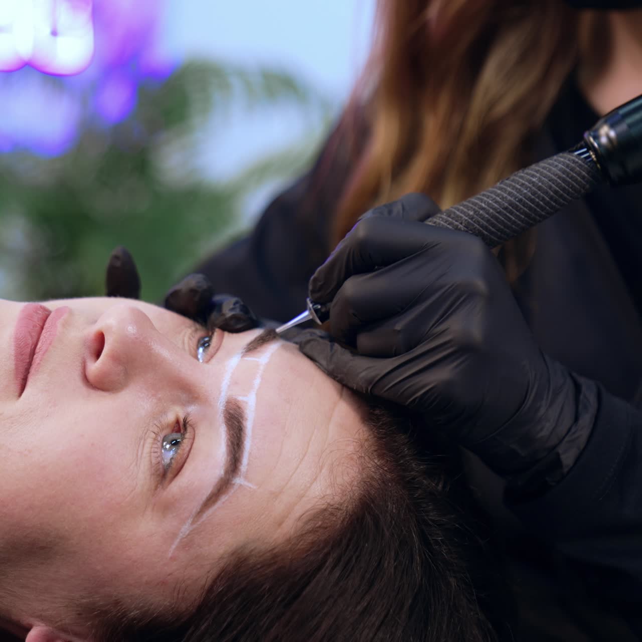 Beautiful adult lady is a client of brow master. Client having the permanent make up procedure for eyebrows. Close up