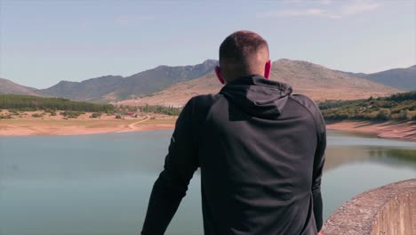 hombre parado en una presa de un lago visitando la hermosa naturaleza