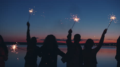 friends celebrating at sunset by the lake with sparkler