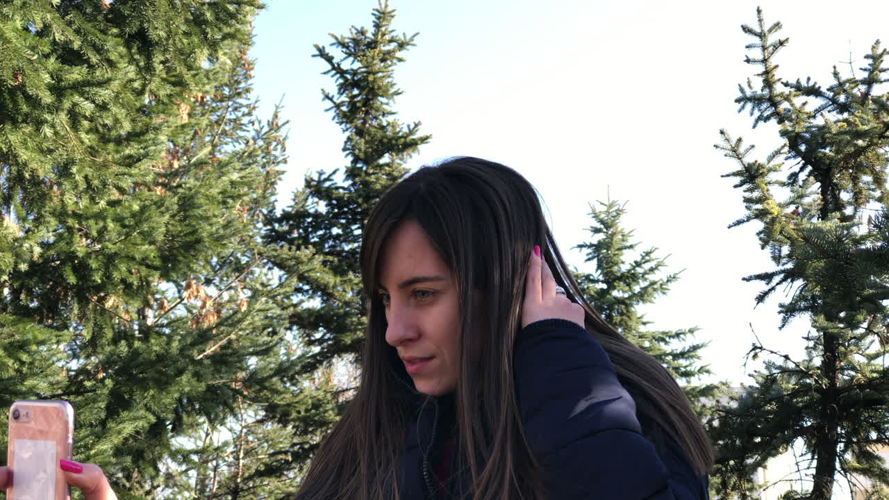 도시 공원에서 전면 카메라를 사용하여 스마트폰으로 셀카를 찍는 어린 소녀