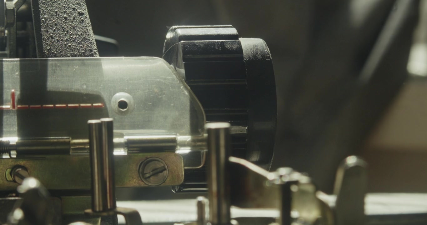 Macro detail of a vibrating mechanical typewriter component in use, highlighting analogue engineering and precision movement.
