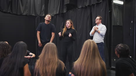 teacher with drama students at performing arts school in studio improvisation class