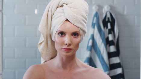 view as though reflected in bathroom mirror of young woman with towelling turban getting ready in the morning