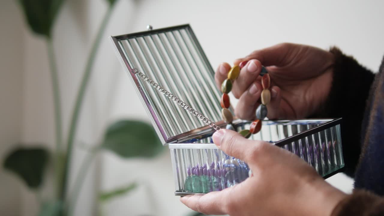 Hænder åbner glassmykkeskrin og tager armbånd ud