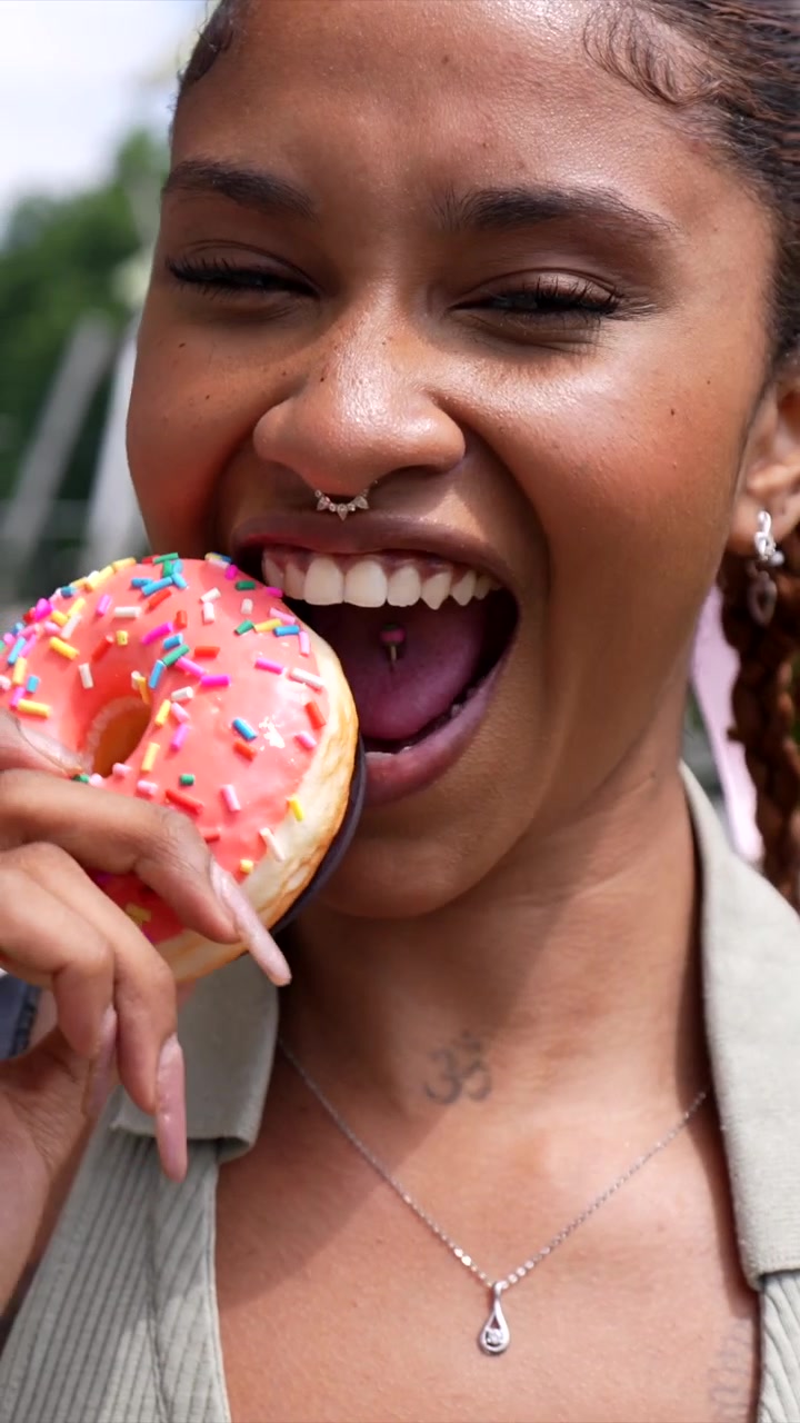 Happy Woman Taking a Bite of a Colorful Donut