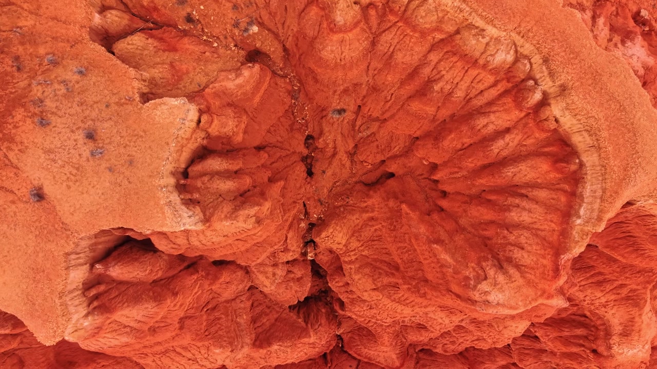 Vista aerea con drone di modelli di erosione in arenaria rossa, Spagna. Prospettiva dall'alto di creste e fessure a forma di ventaglio in roccia arancione vivido.