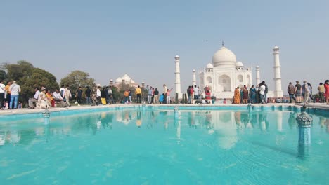 group of tourist admiring the majestic taj mahal monument on a sunny day. panning shot