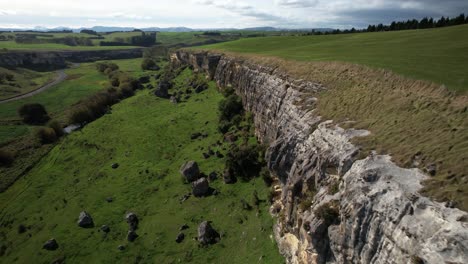 Drone-flyover-limestone-cliff-formation,-beautiful-scenic-of-Otago-rural,-New-Zealand